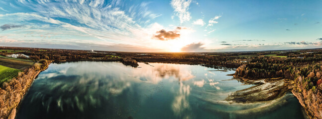 An immersive panoramic aerial view of a dramatic and vibrant sunset painting the sky over a serene...