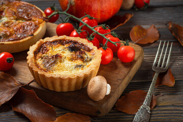 Chicken, mushroom and tomatoes pie quiche with autumn leaves on rustic wooden background