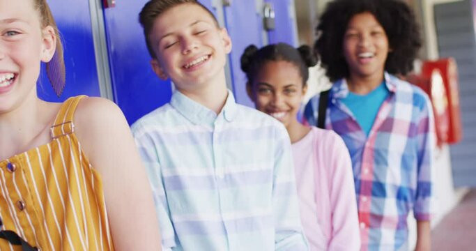 Portrait of happy diverse schoolchildren at locker in school