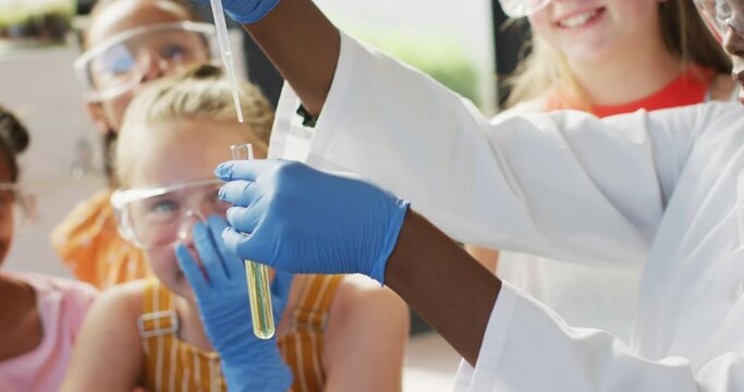 Diverse female teacher and happy schoolchildren having science class in school lab