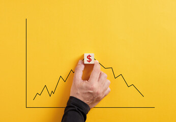 Predicting the market fluctuation in dollar currency. Hand holds the wooden cube with dollar symbol...