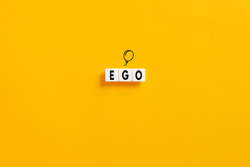 White letter blocks on yellow background with the word ego. Selfishness or inflated ego in...