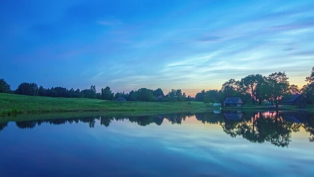 Colorful predawn to sunrise time lapse of a lakeside farmhouse with the sky reflecting off the water
