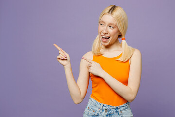 Young blonde woman she wear orange tank shirt casual clothes point index finger aside indicate on workspace area copy space mock up isolated on plain pastel light purple background. Lifestyle concept.