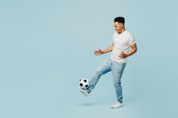 Fototapeta na wymiar Full body side profile view fun cheerful young man fan wearing t-shirt cheer up support football sport team hit soccer ball on leg watch tv live stream isolated on plain pastel blue color background
