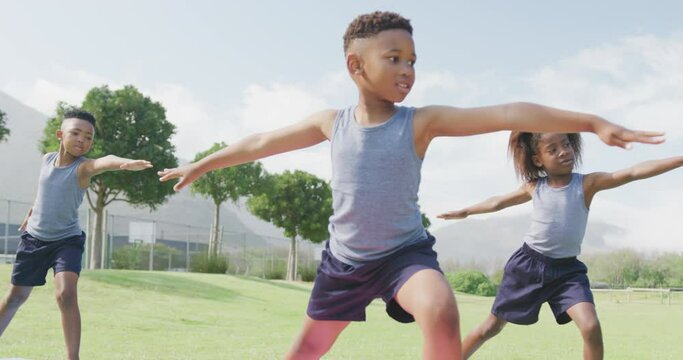 Video of three african american schoolchildren practicing yoga standing in outdoor class
