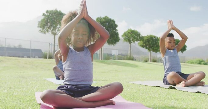 Video of three african american schoolchildren practicing meditation in outdoor class