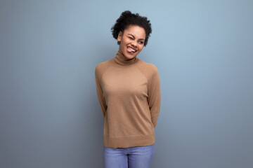 positive young bright latino woman with afro hair gathered in a ponytail against the background with copy space