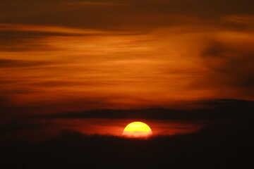 A Radiant Farewell: Half Sun Setting in the Horizontal Orange Sky, Embracing the Coming Darkness