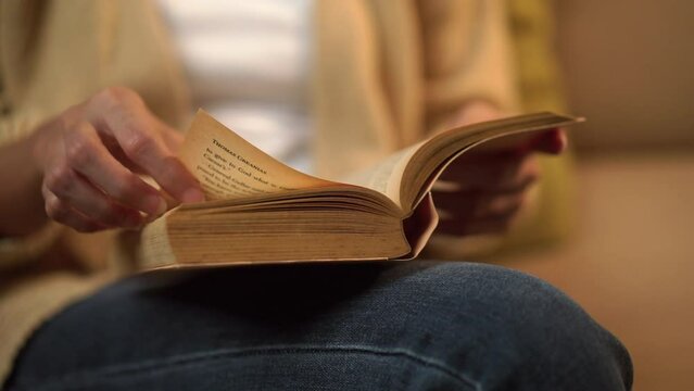 Close-up Happy woman opening, reading and relaxing a book on relax time at home. Vacation time of female reading a book on sofa at night. Education concept.
