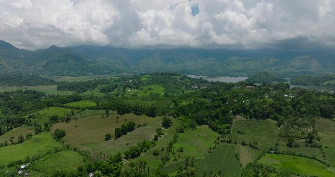 Farmland in mountain and lake surrounded by forest and jungle. Blue sky and clouds. Lake Sebu. Mindanao, Philippines.