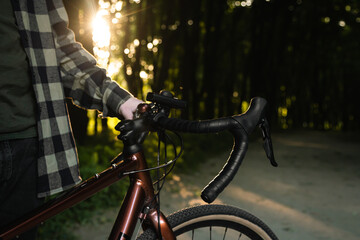 A man with a bicycle in the forest at sunset, the concept of outdoor activity, travel and sports.
