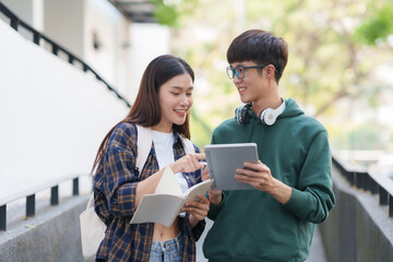 Happy Two Young Asian Students Collaborating Outdoors at University. Teamwork and Knowledge Sharing. Asian Students Engaged in Collaborative Learning Outdoors.