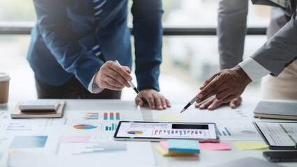 Group of business people working together on new project with planning analytical report at meeting. Businesspeople meeting together pointing to graph assess business profits.