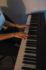 Obraz na płótnie Canvas Plano detalle de manos tocando el piano con luz tenue anaranjada
