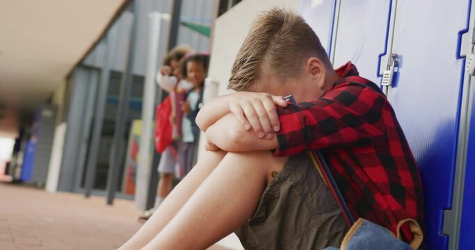 Video of sad caucasian schoolboy being taunted by two diverse children at school