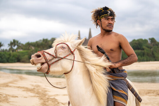 Marapu Sumba Tribe gracefully rides a horse along the shoreline