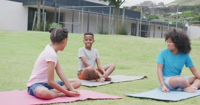 Video of diverse, happy schoolgirls and schoolboy talking during outdoor yoga class, copy space