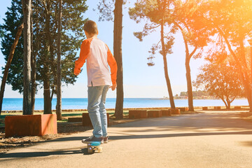 Boy riding skateboard outdoors in summer day in the road, Child learns to ride a penny board, Travel, sports concept.