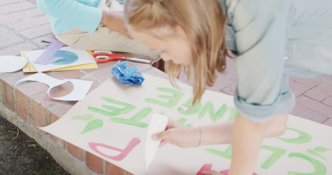 Video of caucasian schoolgirl making protest placard in schoolyard, copy space