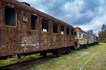 Old rusty passenger car with EMUs abandoned on railway tracks