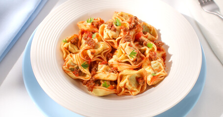 tortelloni with bolognese sauce. classic Italian pasta with spinach and ricotta in tomato-meat sauce. dish of mediterranean cuisine on a light background. food on the table on a sunny day.