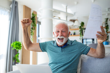 Surprised laughing happy old mature retired man looking through paper document, feeling excited analyzing financial information, getting taxes refund or bank loan approval at home.