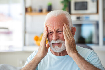 senior man suffering from a headache at home. Worried senior man sitting alone in his home. This...