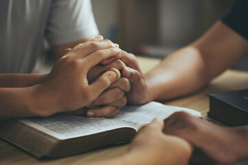 Obraz na płótnie Canvas Christian group of people Holding hands together and praying on the holy bible. devotional for prayer meeting concept. praying worship to believe. Encouraging each other to get through the crisis.Love