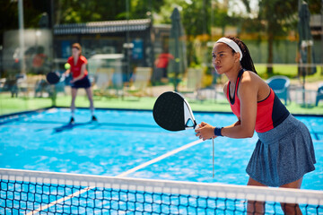 Black female athlete plays padel tennis doubles on outdoor court.