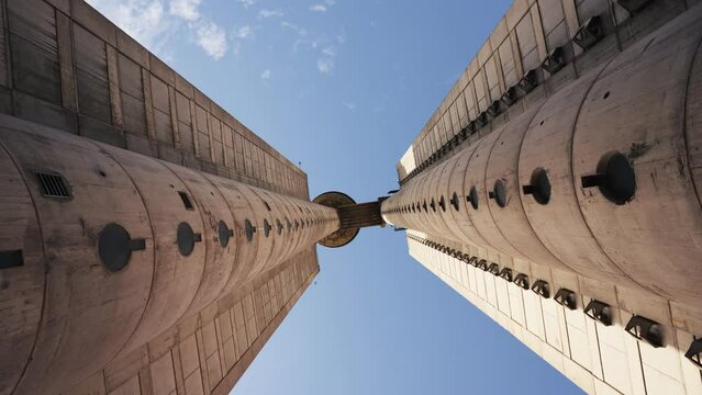 Low angle view of grunge symmetrical concrete building. Sunny day and blue sky. Straight up view. Soviet architecture.