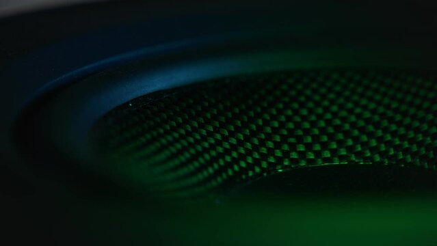 Extreme close-up loopable shot of the subwoofer membrane illuminated with the colorful disco light.