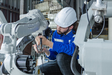 Male technician engineer checking automation robotics arm at industrial modern factory. man working at factory innovation automation robot. Maintenance department, robots used in industrial.
