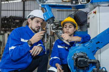 Team technician engineer checking automation robotics arm at industrial modern factory. Two technician working at factory innovation automation robot. Maintenance department.