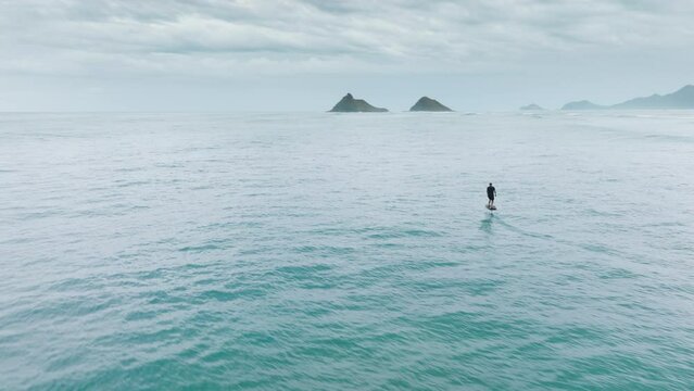 Water sport activity. Extreme sport activity shot on drone camera. Water sports on Oahu, Hawaii island. Surfer wake boarding on foil board. Athletic man rides a foilboard by using power of ocean waves