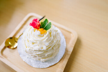 Fresh cream cake or fresh milk cake in cute style on wooden plate with spoon on wooden background.
