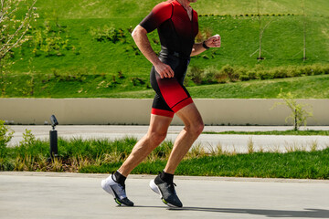 Fototapeta premium side view athlete runner running marathon race in urban landscape park, summer sports event