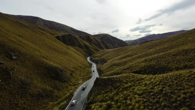 Aerial tracking shot of a convoy of trucks driving through picturesque New Zealand