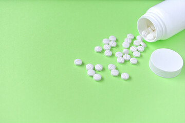 緑の背景と白い錠剤と白い薬のボトル