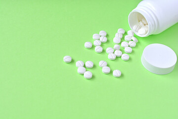 緑の背景と白い錠剤と白い薬のボトル