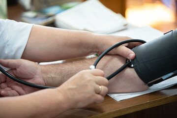 A doctor using a sphygmomanometer with a stethoscope revealed arterial hypertension in a patient in...