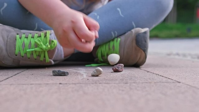 Caucasian Girl Mastering Dexterity Game of Jackstones Scatter Jacks Knucklebones using Small Rocks