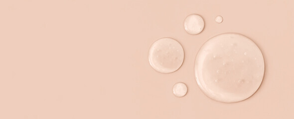 round drops of transparent gel serum on beige background