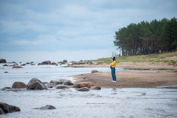 Young girl with smartphone on the sandy shore sea - 621816185