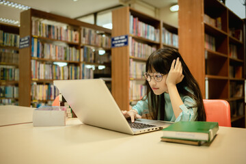 Little girl posing in public library room selecting for reading. girl chooses books on shelves...