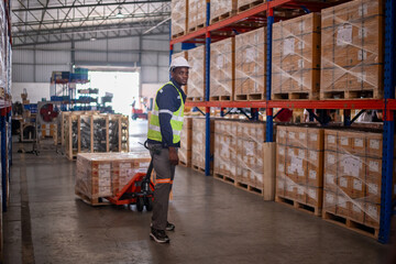 Warehouse workers working factory cargo hand pulling pallet truck, stack cardboard boxes on wooden pallet is cargo shipment import export transportation concept.