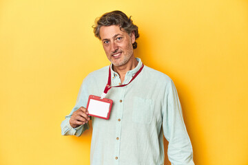 Man with an event ID card around his neck against a yellow backdrop.