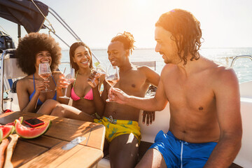 Happy multiracial friends having fun drinking champagne at boat party outdoor - Focus on african man hand holding glass