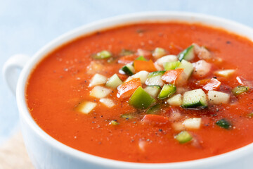 Traditional Spanish gazpacho soup in bowl on blue background. Close up