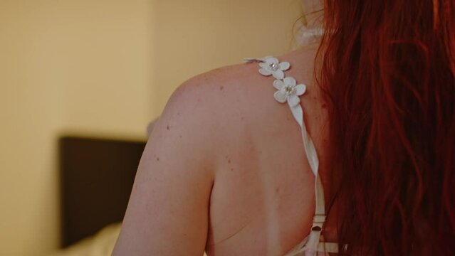 Back of beautiful redhead girl bouncing on bed while wearing lingerie